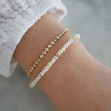 Birthstone Bead Bracelet In Pearl styled on wrist of model with diamond bracelet and wearing white sleeve