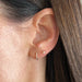 Diamond Sparkle Stud Earring in 14k yellow gold styled on ear lobe next to diamond mini huggie earring on ear lobe of model with brown hair