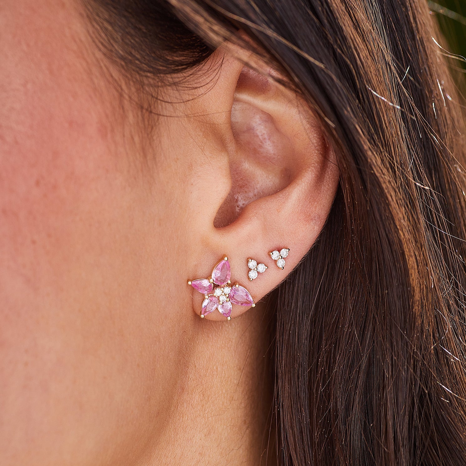 Pink Sapphire & Diamond Trio Cluster Stud Earring in 14k yellow gold styled on first earring hole of model next to two diamond trio earrings